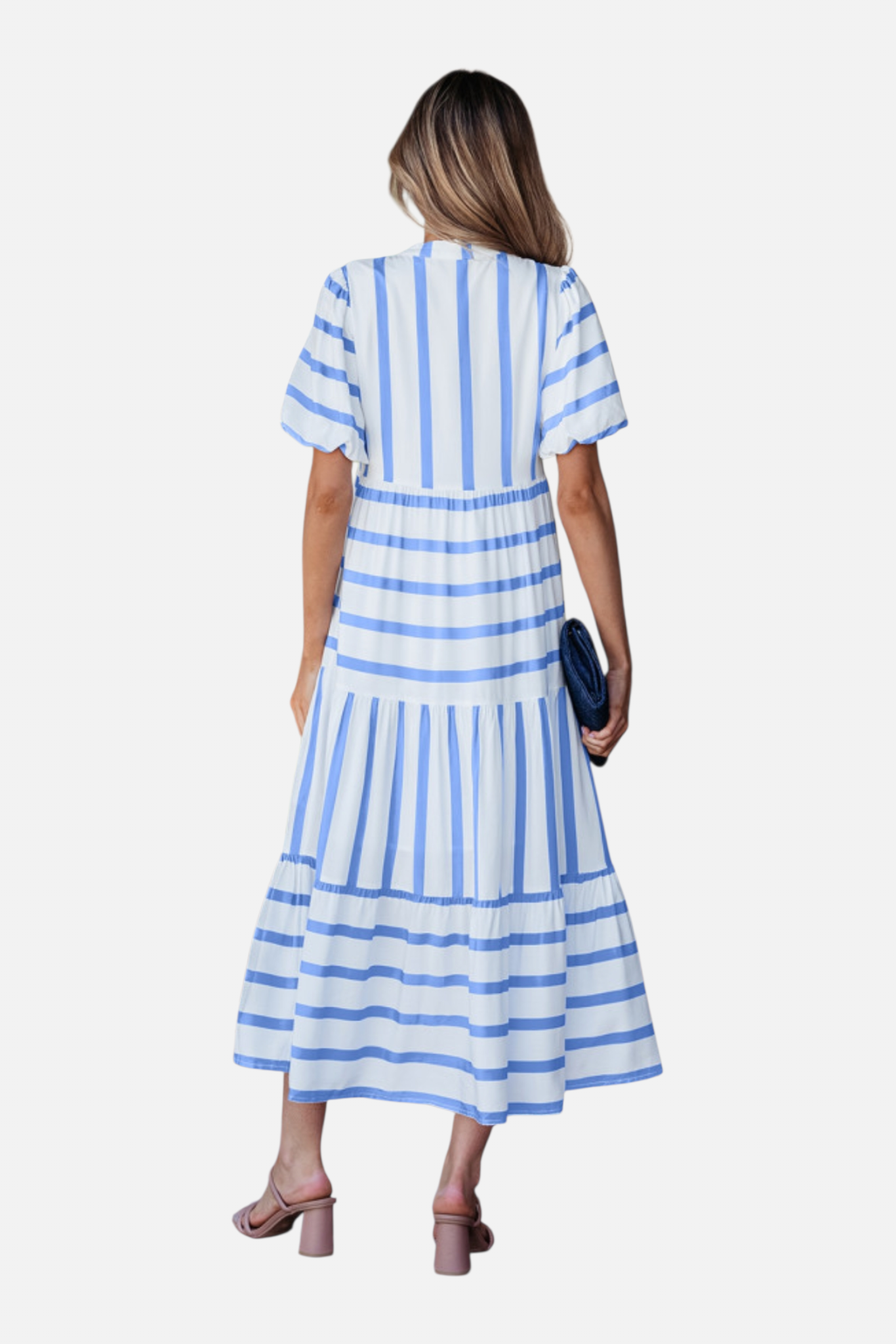 Rear view of a model showcasing the sky blue striped midi dress, featuring a notched V-neckline with blue ricrac trim, puff sleeves, and a tiered skirt in a vacation-ready 100% viscose fabric.