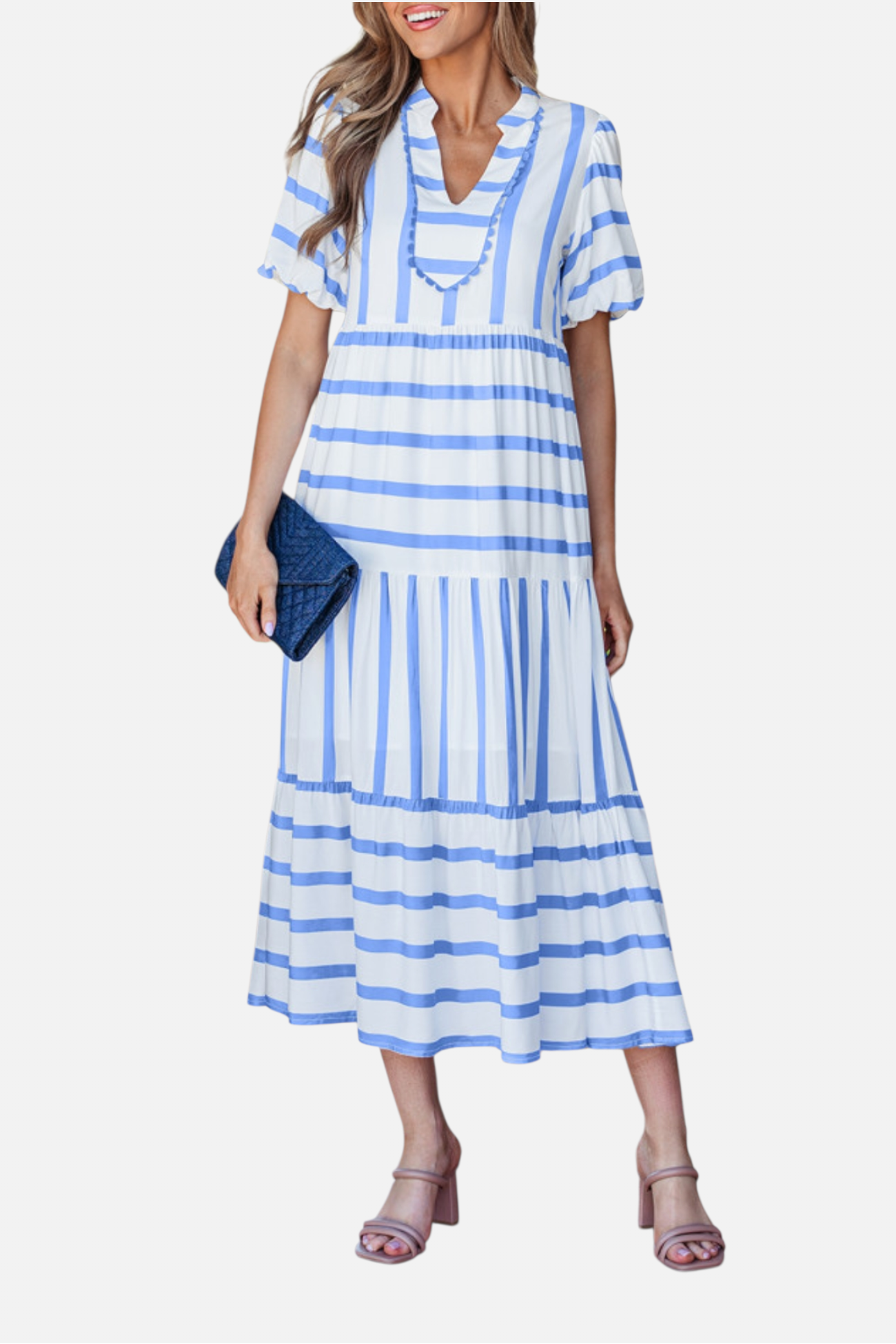 A model showcasing the sky blue striped midi dress, featuring a notched V-neckline with blue ricrac trim, puff sleeves, and a tiered skirt in a vacation-ready 100% viscose fabric.