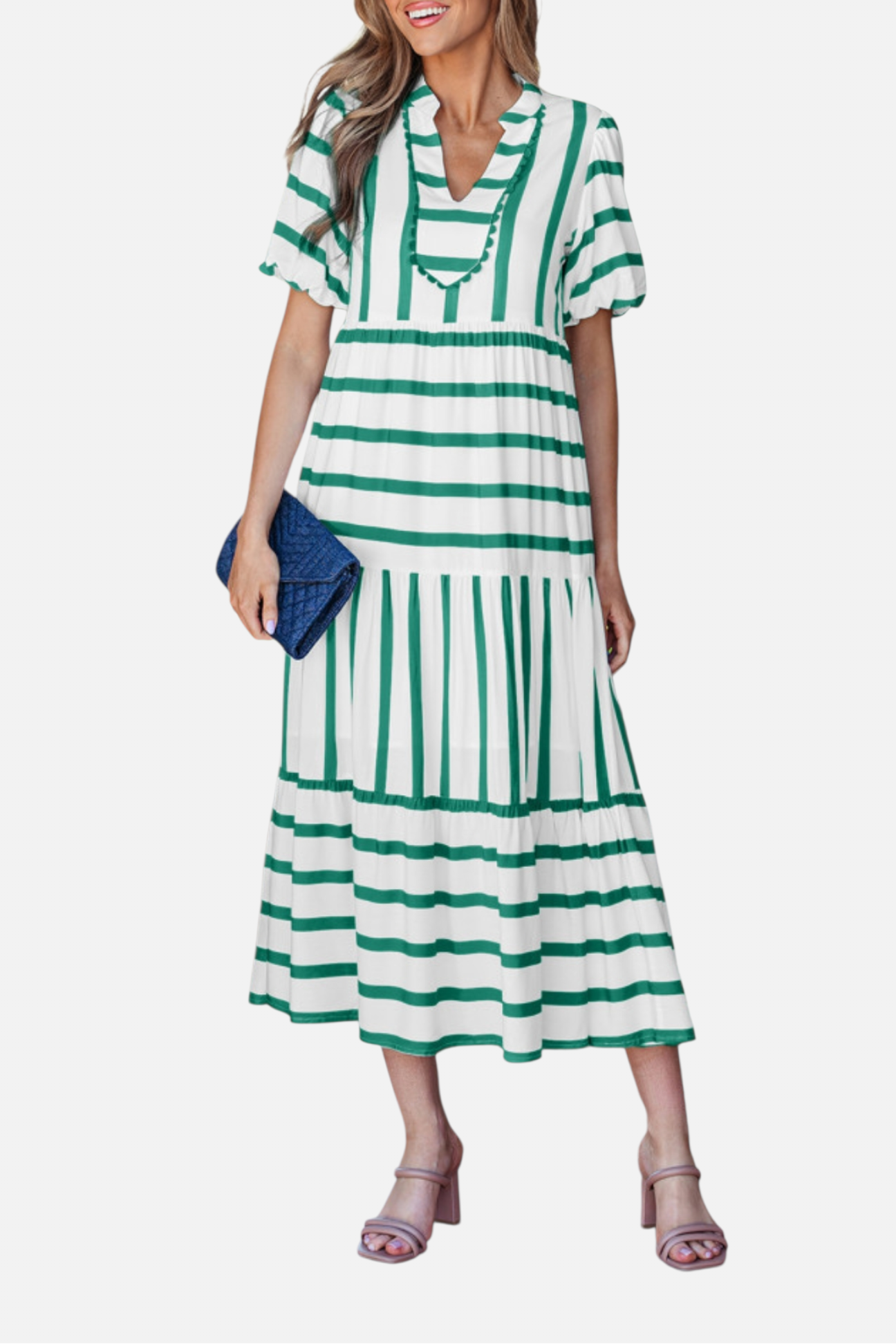 A model showcasing the green striped midi dress, featuring a notched V-neckline with blue ricrac trim, puff sleeves, and a tiered skirt in a vacation-ready 100% viscose fabric.
