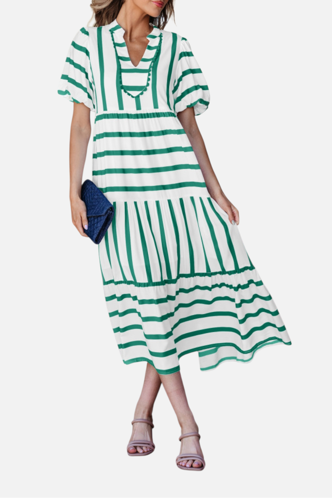 A model showcasing the green striped midi dress, featuring a notched V-neckline with blue ricrac trim, puff sleeves, and a tiered skirt in a vacation-ready 100% viscose fabric.