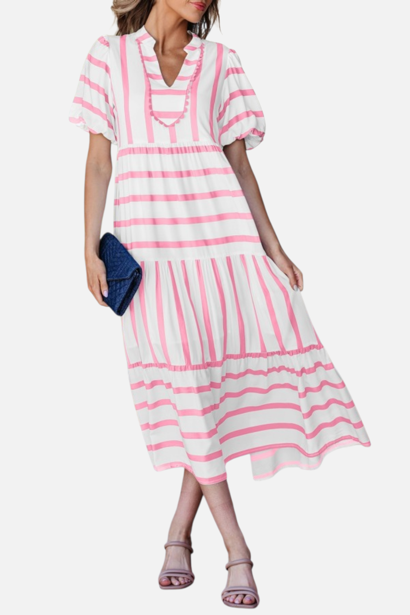 A model showcasing the pink striped midi dress, featuring a notched V-neckline with pink ricrac trim, puff sleeves, and a tiered skirt in a vacation-ready 100% viscose fabric.