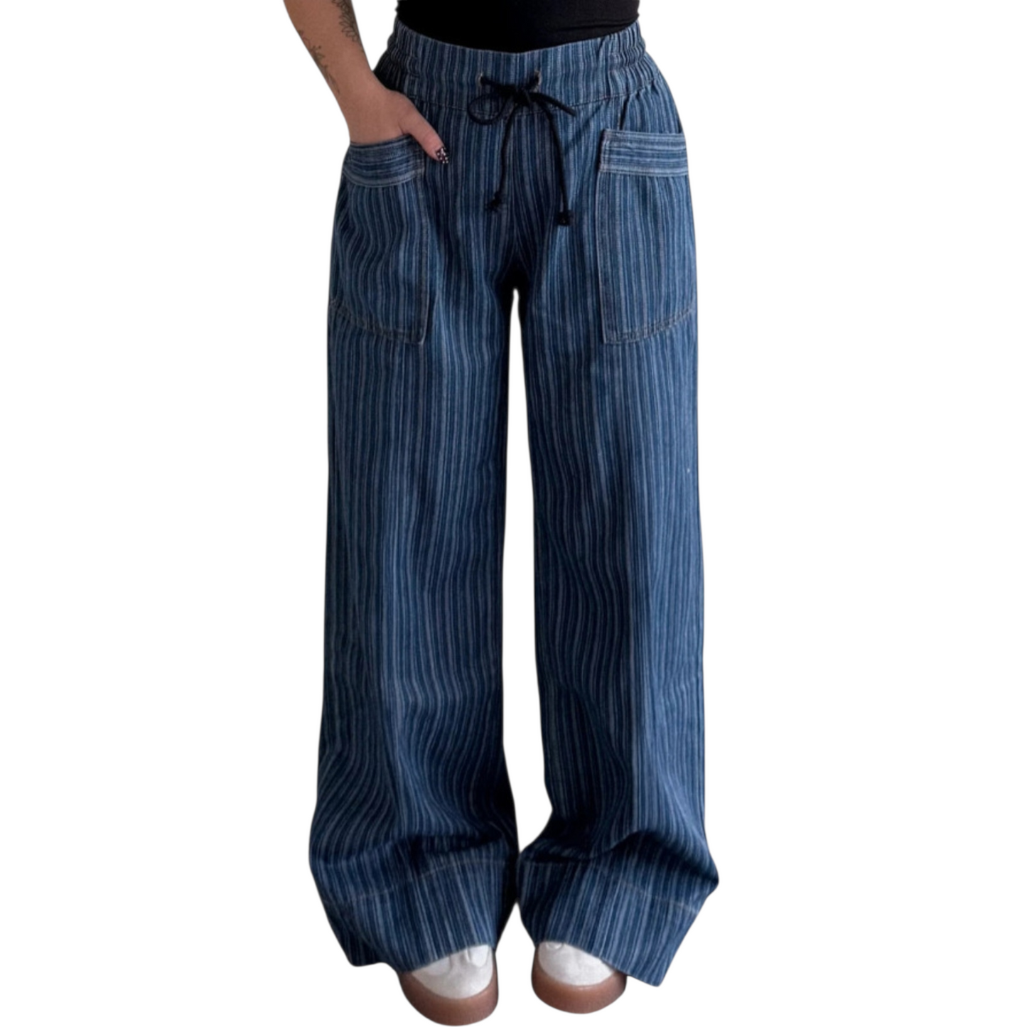 Person wearing wide-leg, blue pinstriped drawstring pants with cuffed hems, paired with white sneakers.