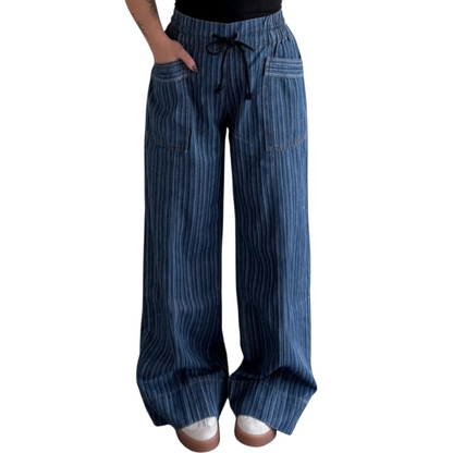 Person wearing wide-leg, blue pinstriped drawstring pants with cuffed hems, paired with white sneakers.