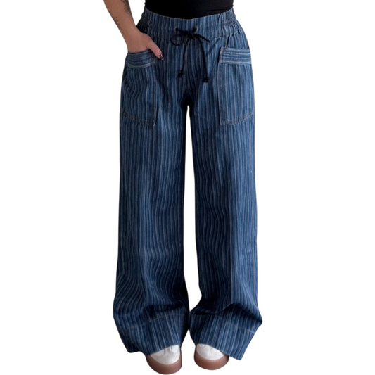 Person wearing wide-leg, blue pinstriped drawstring pants with cuffed hems, paired with white sneakers.
