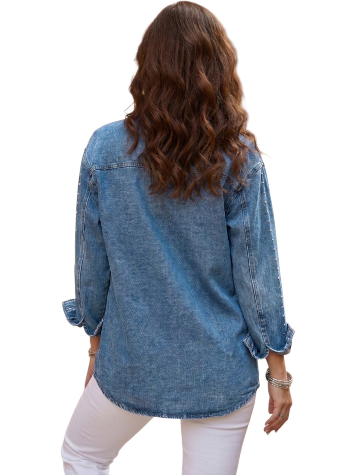 A woman viewed from behind wearing a light blue denim shirt with rolled-up sleeves and white pants, set against a plain white background.
