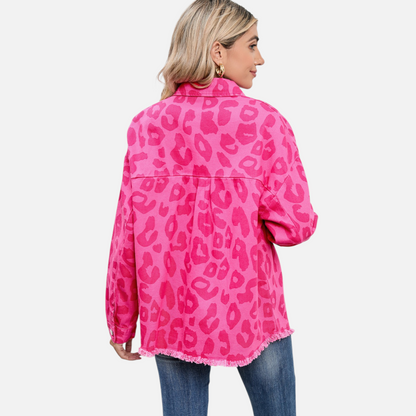 The back view lifestyle shot of a woman wearing the pink leopard print denim jacket with high-waisted blue jeans, highlighting the consistent print placement and unique raw hemline finish from behind.