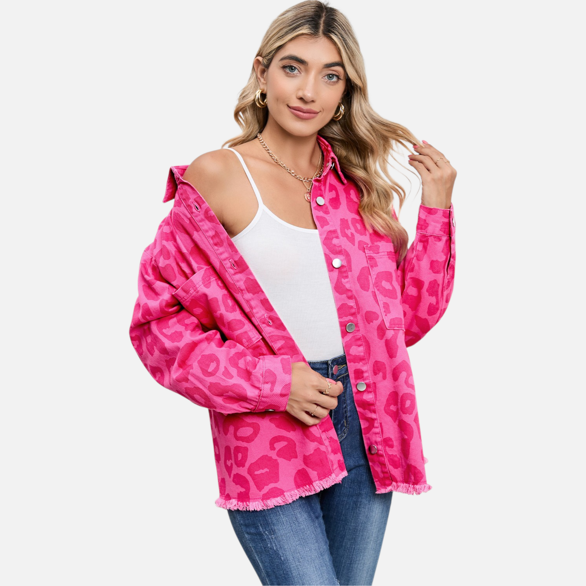 A model confidently poses in the unbuttoned pink leopard print denim jacket, revealing a white camisole and blue jeans, perfect for showing versatile layering and casual style.