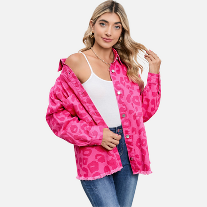 A model confidently poses in the unbuttoned pink leopard print denim jacket, revealing a white camisole and blue jeans, perfect for showing versatile layering and casual style.