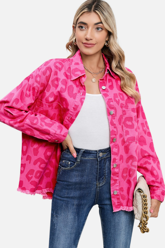Woman wearing a bright pink leopard print jacket on a light gray background