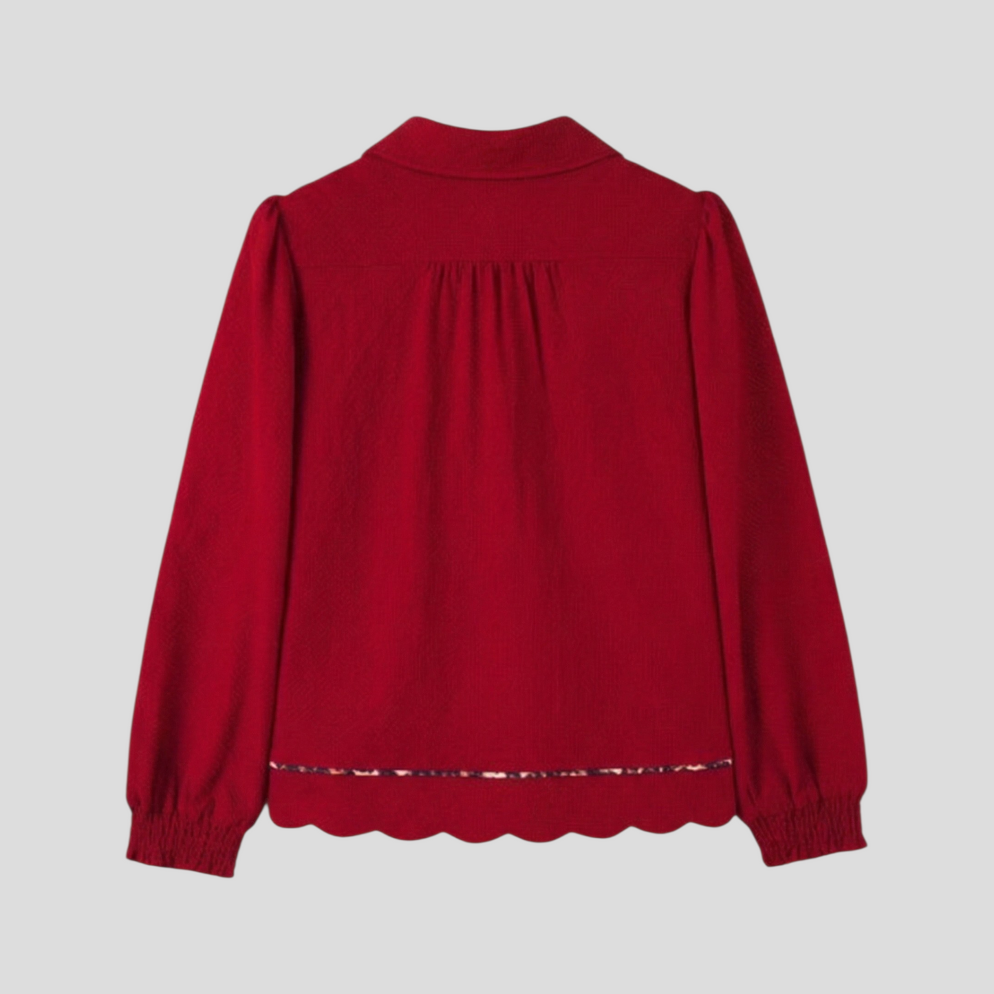 Rear flat lay of a red textured blouse, showing the collared back and a scalloped bottom hem with leopard print trim.