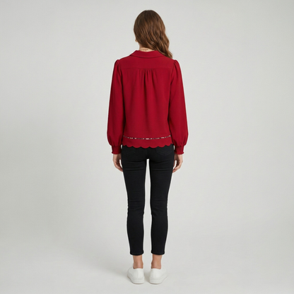 Rear view of a model wearing a red textured collared blouse, showcasing the fitted silhouette and scalloped hemline.