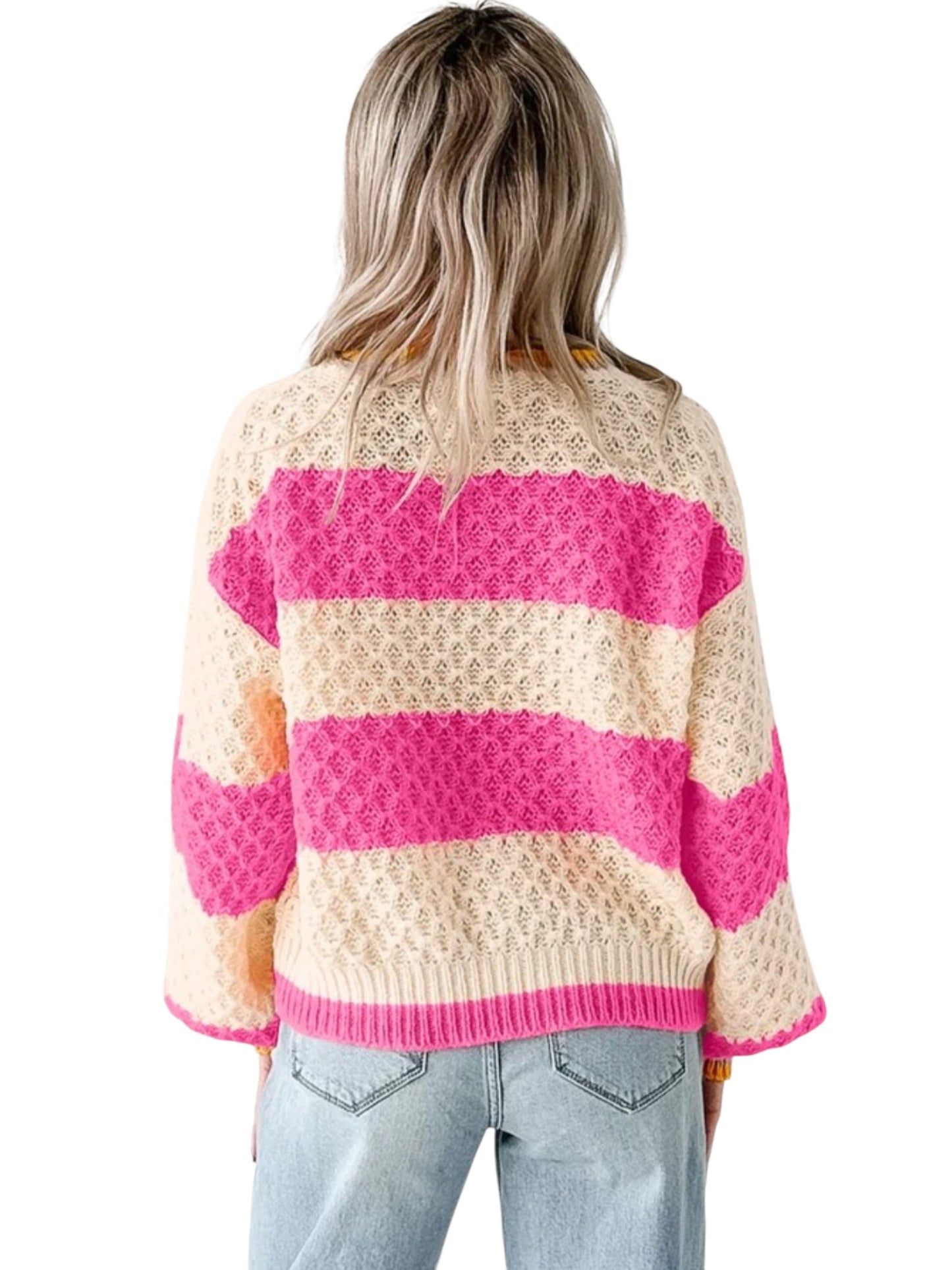 A woman viewed from behind wearing a cream and bright pink striped knit sweater with textured openwork patterns and light blue jeans, against a plain white background.