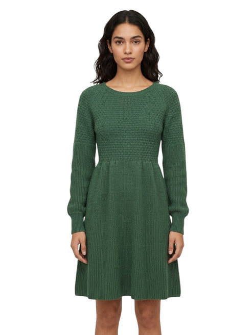 A woman modeling a green long-sleeve knit dress with a textured pattern, standing against a plain white background.