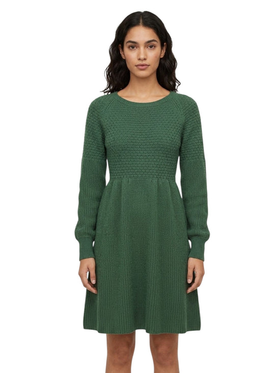 A woman modeling a green long-sleeve knit dress with a textured pattern, standing against a plain white background.