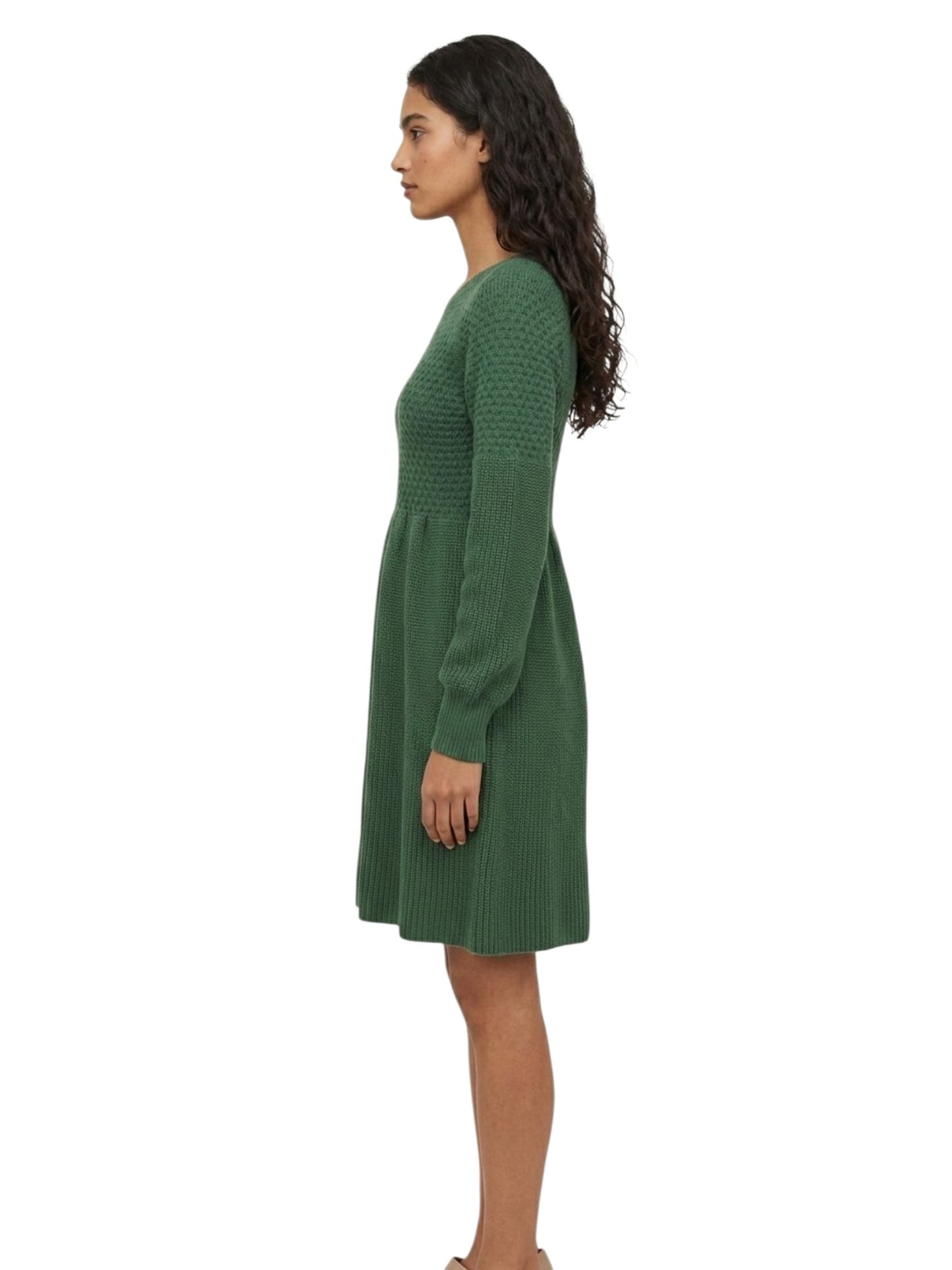 A woman shown in side profile wearing a green ribbed knit long-sleeve dress against a plain white background.