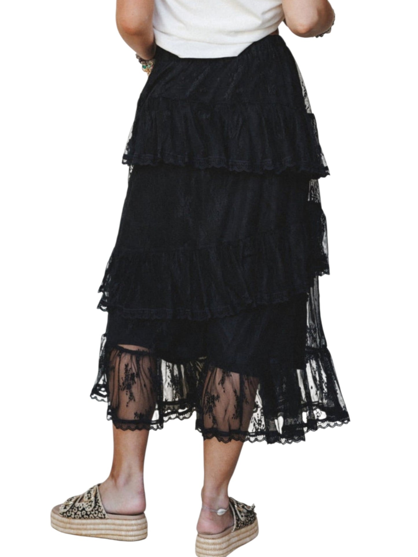 A black tiered ruffle midi skirt with sheer lace hem, shown on a model wearing a white top and espadrille mule sandals against a white background.