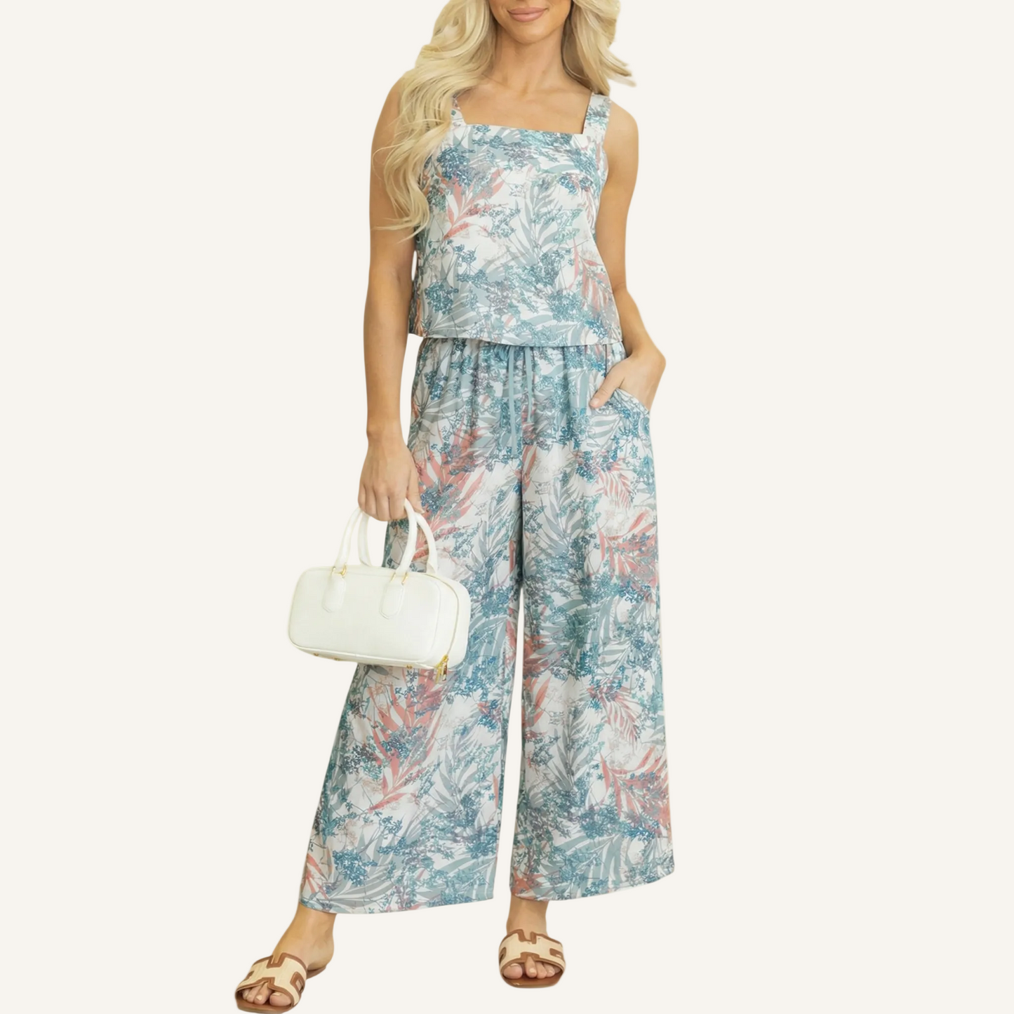 Front view of a woman wearing a two-piece tropical print set featuring a square-neck tank top and matching wide-leg pants with a botanical leaf pattern.