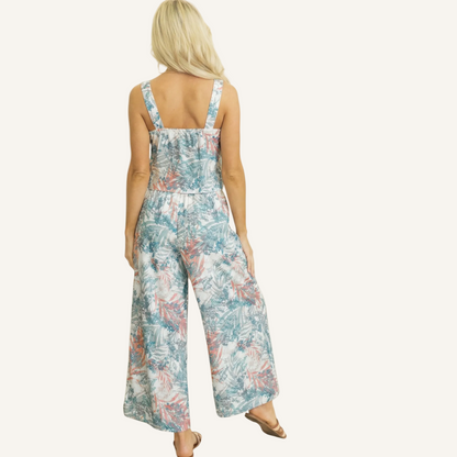 Rear view of the tropical print outfit highlighting the hi-lo hemline of the tank top and the relaxed, flowy fit of the high-waisted wide-leg trousers.