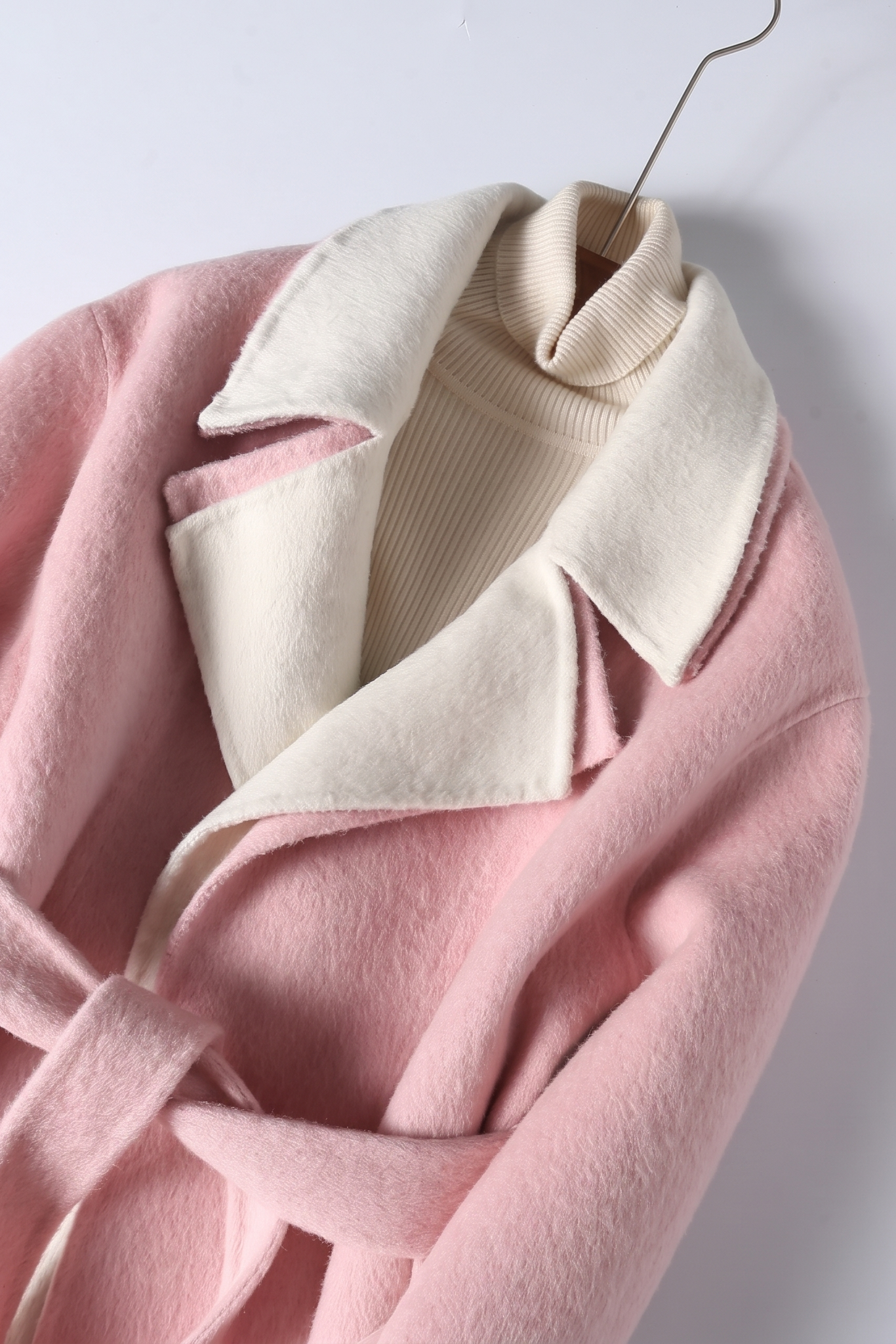 Close-up of the double-faced wool coat highlighting the contrast between the pink exterior and the soft cream-colored notched lapel.