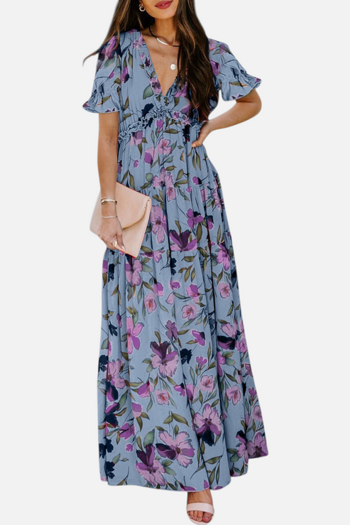 Front view of a model wearing a blue tiered maxi dress with purple floral print, featuring a deep V-neckline and frill detailing.