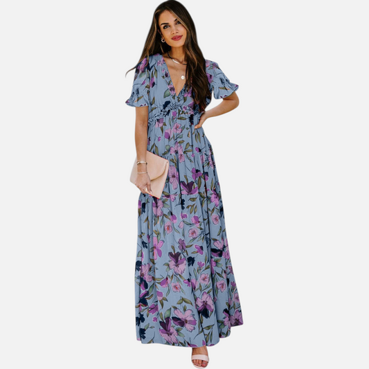 Front view of a model wearing a blue tiered maxi dress with purple floral print, featuring a deep V-neckline and frill detailing.