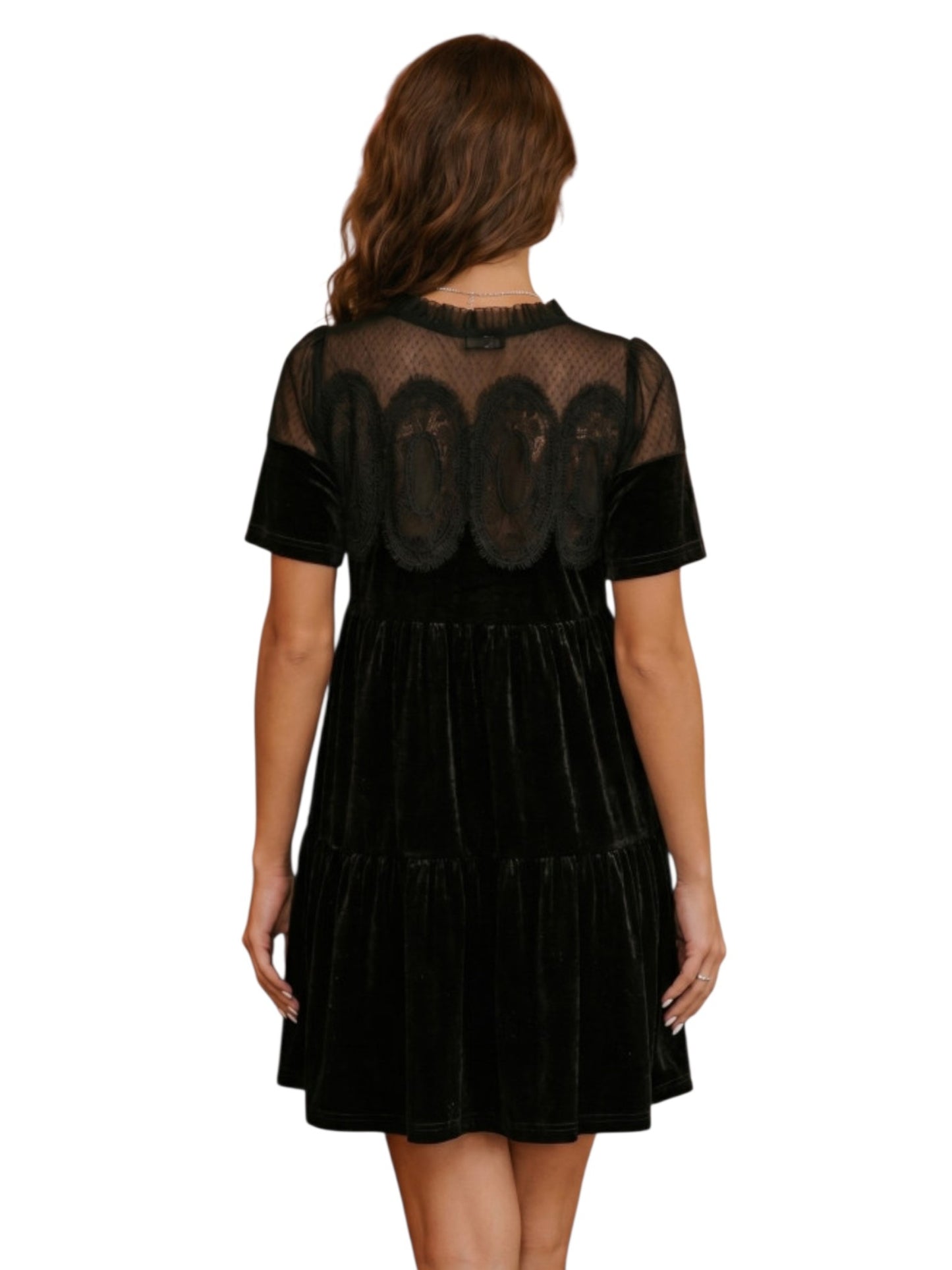 A woman viewed from the back wearing a short-sleeve black dress with sheer mesh sleeves and a tiered skirt, photographed against a plain white background.