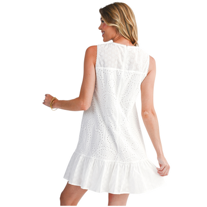 Rear view of a sleeveless white eyelet mini dress showing the intricate embroidery detail, high neckline, and ruffled hemline.