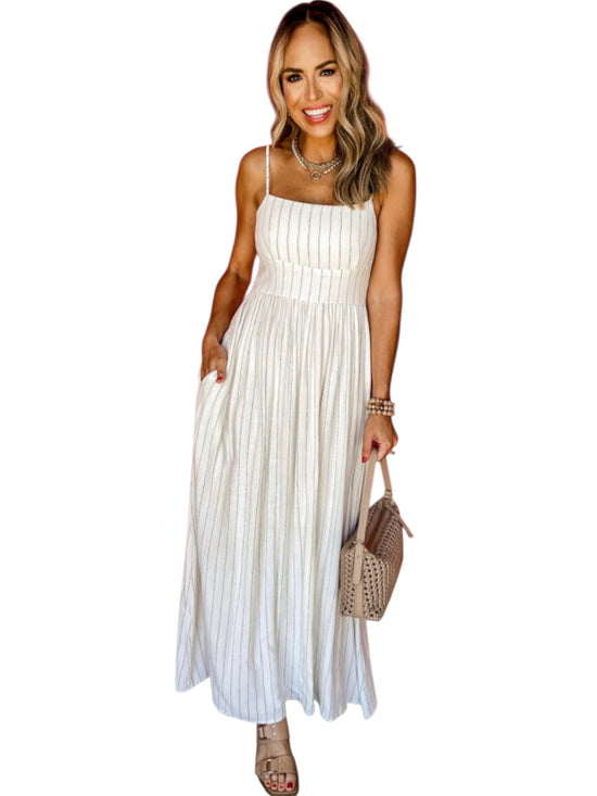 Woman wearing a white pleated dress holding a beige handbag on a white background front view