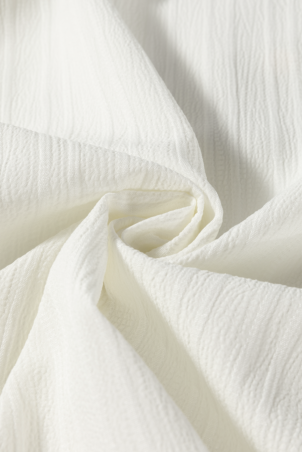 Fabric view of a white long sleeve texture blouse for women.
