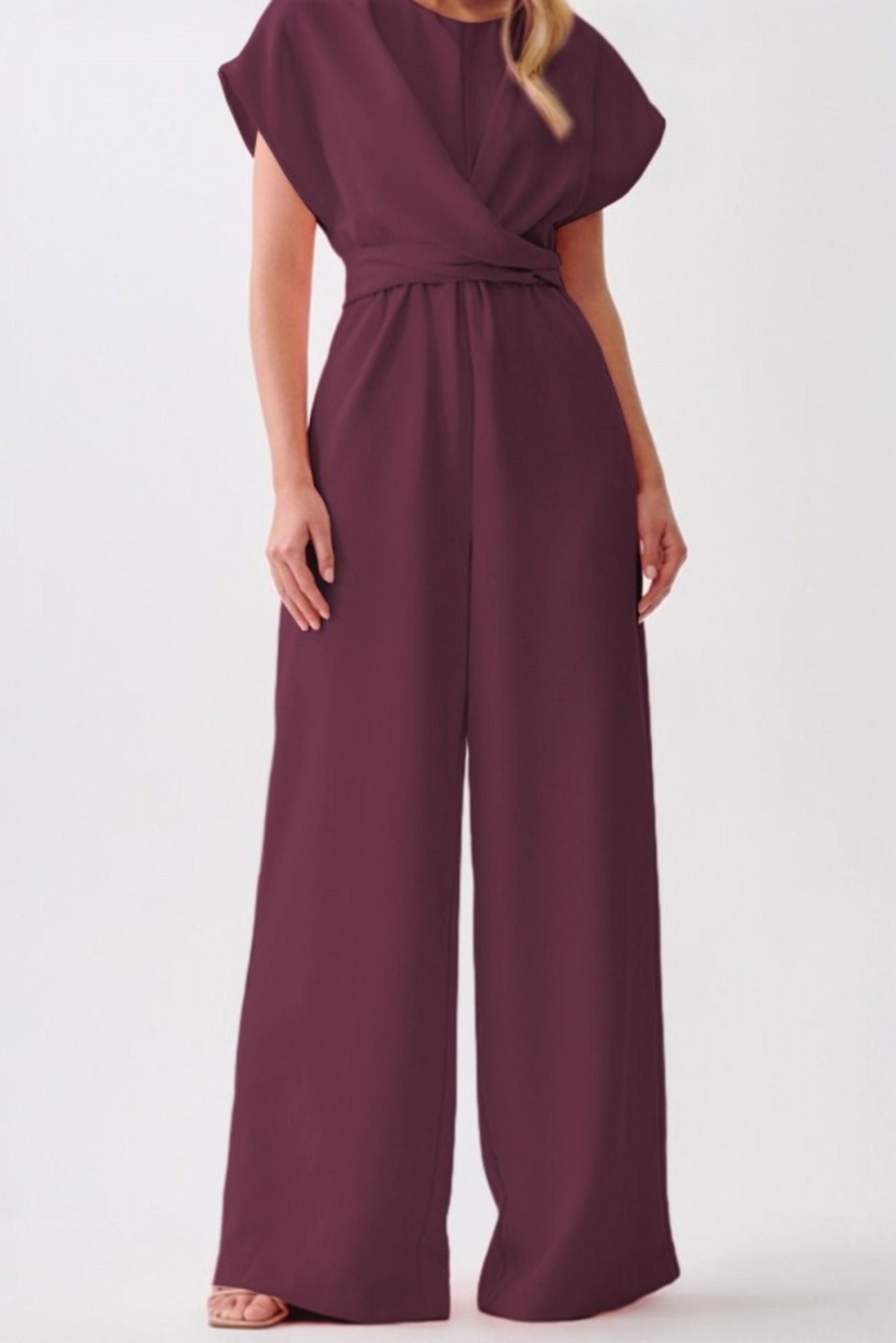 Close-up of the front-wrap knot detail and high-waist tailoring on a sophisticated cap-sleeve jumpsuit.
