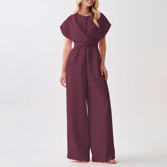 A model showcasing a formal plum jumpsuit with an elegant wide-leg cut, cinched waist, and minimalist round neckline.
