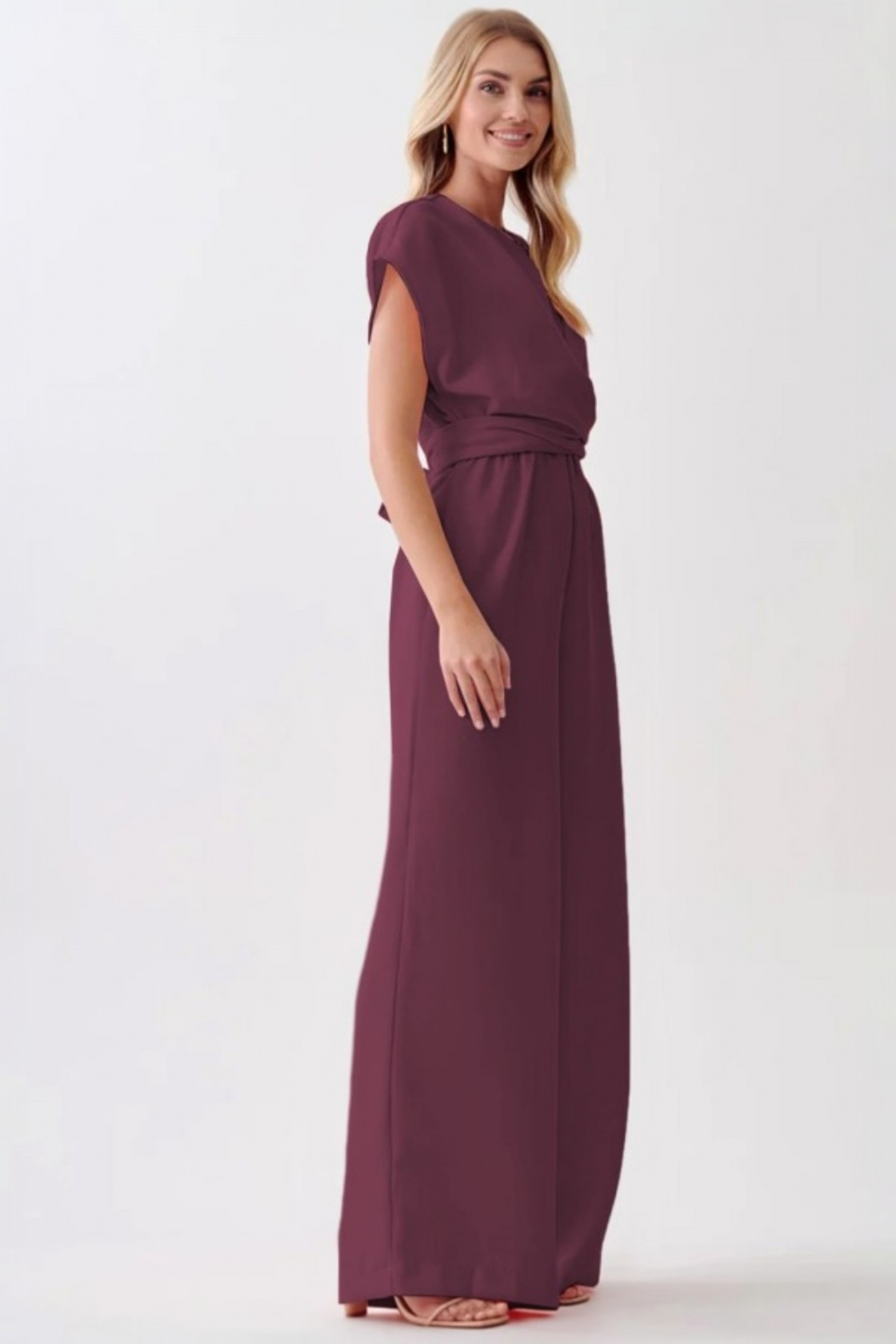 Side profile of the cinched-waist jumpsuit, emphasizing the fluid movement of the wide-leg pants and the polished, flattering fit.