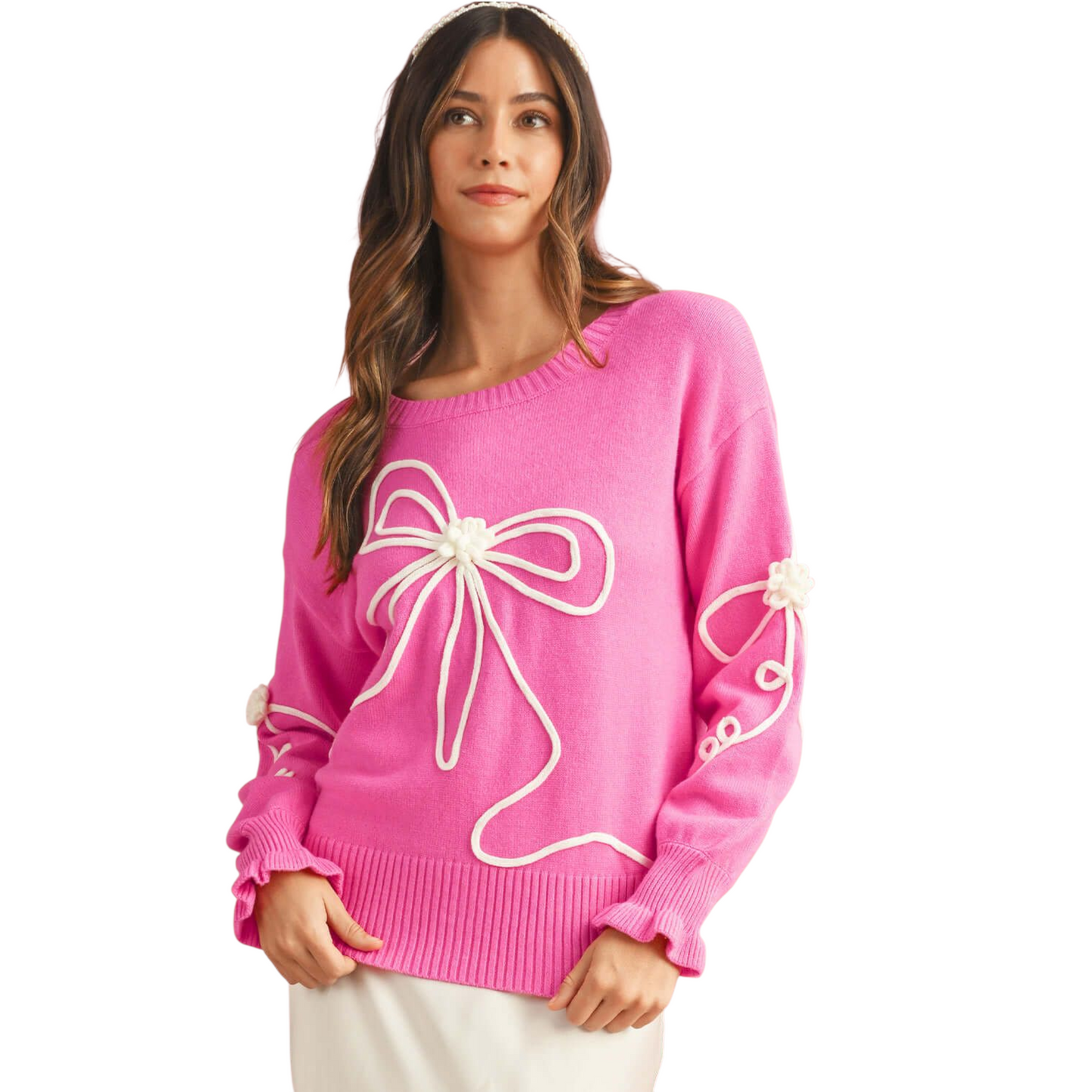 Woman wearing a pink sweater with a large white bow design on a white background