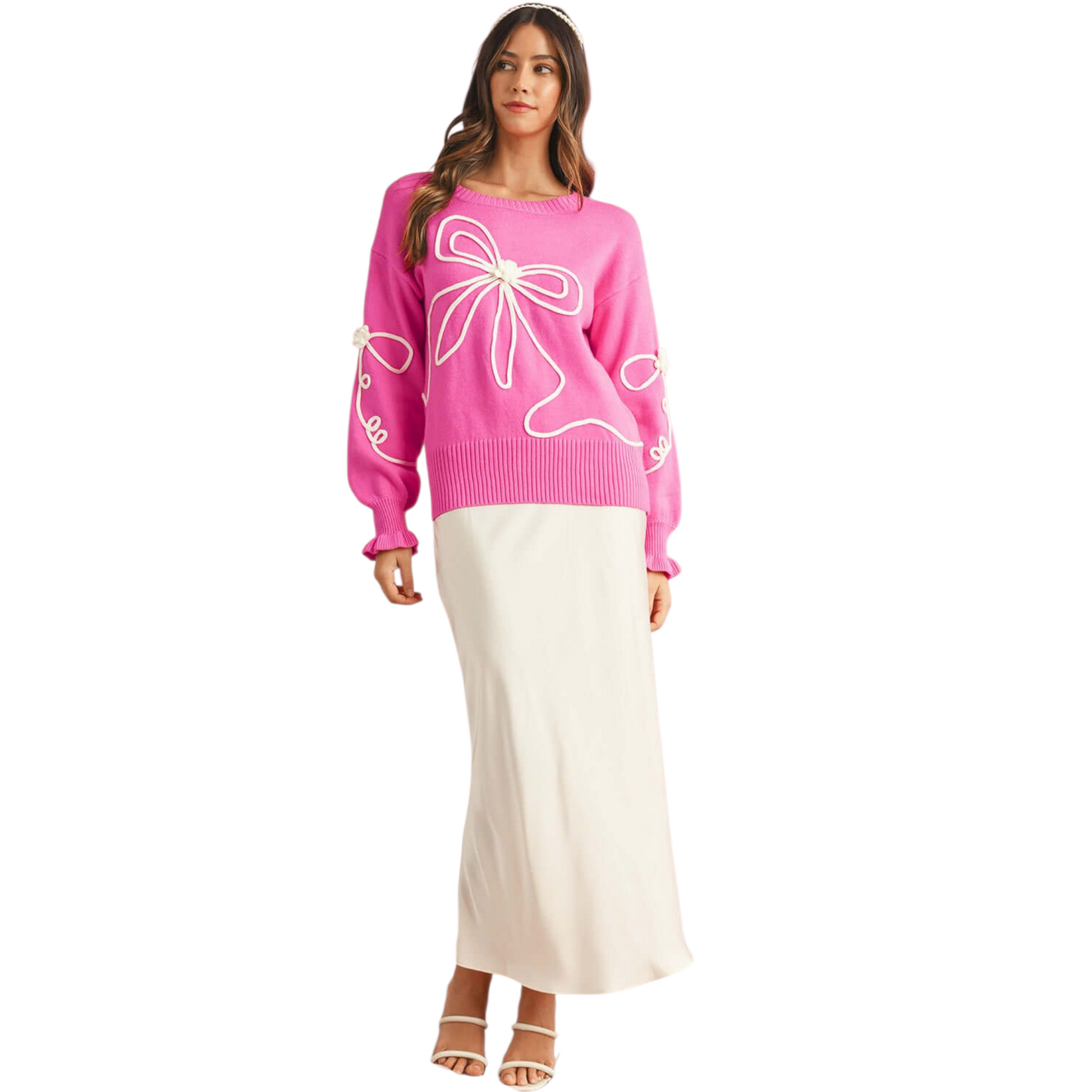 Woman wearing a pink sweater with white floral designs on a white background