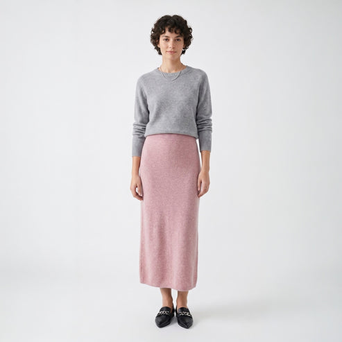 Model styling the rose pink knit midi skirt with a grey crew neck sweater and black loafers for a smart casual look.