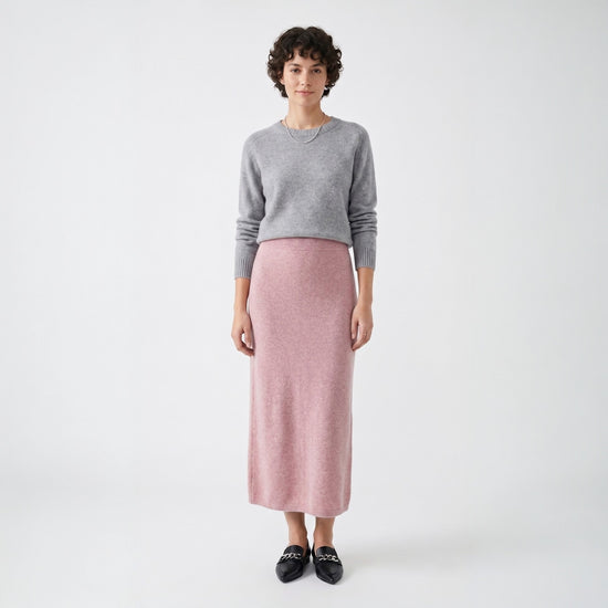 Model styling the rose pink knit midi skirt with a grey crew neck sweater and black loafers for a smart casual look.