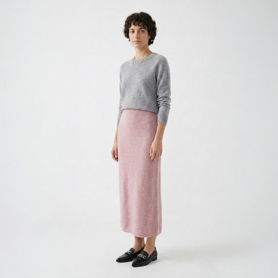 Model styling the rose pink knit midi skirt with a grey crew neck sweater and black loafers for a smart casual look.
