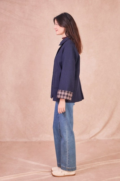 Side view of a navy wool-blend jacket showing the back pleat detail and relaxed, slightly oversized silhouette.