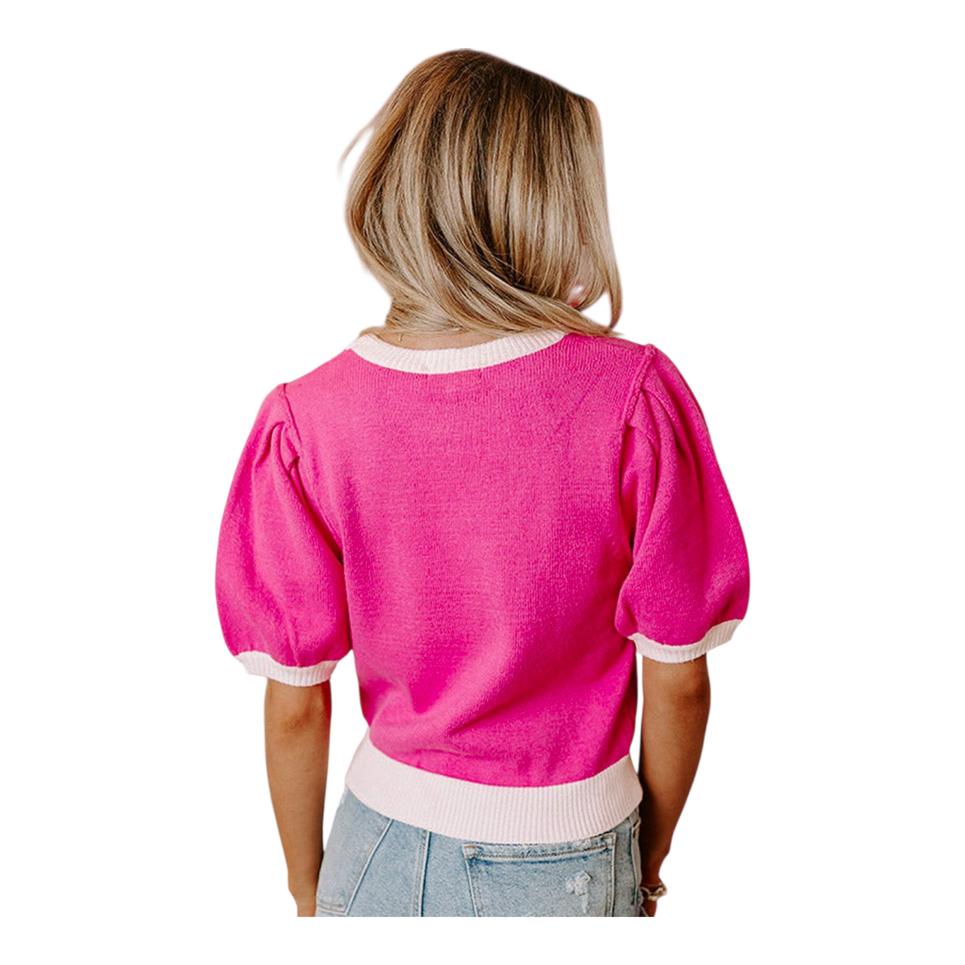 Person wearing a bright pink sweater with white trim on a white background
